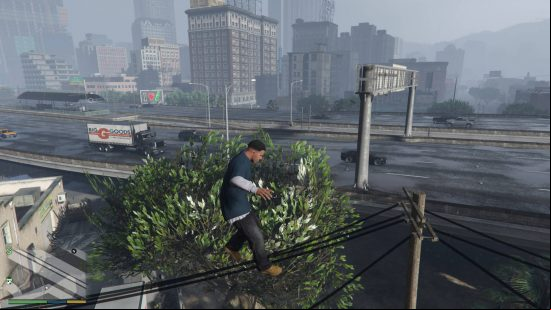 GTA 5 cheats - Franklin is jumping extremely high into the air, clearing the telephone cables and tree behind him. There is also a freeway and tall buildings behind him.