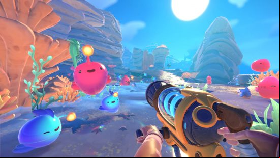 Best games like Pokémon - several happy-looking slimes are bouncing around Rainbow Island in Slime Rancher 2.