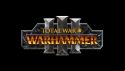 The new and official Total War: Warhammer 3 logo - three steel-grey numerals over a field of grey metal weapons and shields