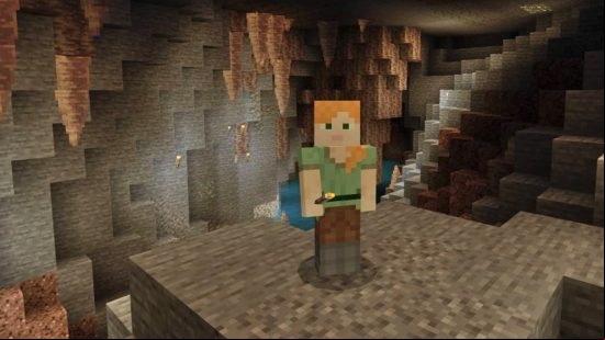 Minecraft Dripstone caves: Alex standing in the Minecraft dripstone cave with stalactites in the background and mineable copper on the wall behind her.
