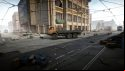 Escape from Tarkov screenshots: A large orange flatbed utility truck parked in the street underneath tram lines in front of a tall downtown building