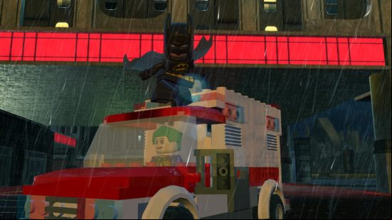 Best Batman games - Batman on top of an ambulance being driven by The Joker in LEGO Batman 2. It's ing under a bridge. 