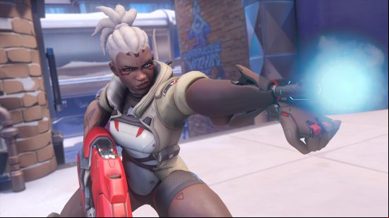 Overwatch 2 characters: a woman with a robotic arm fires the gun that is protruding from her wrist.