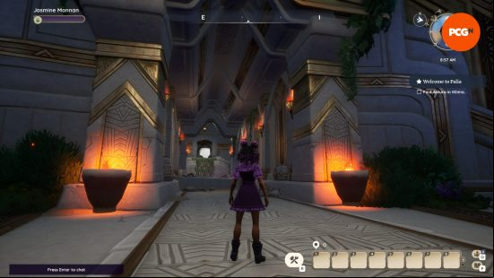 A tanned woman wearing a purple dress over a checked lilac and pink shirt stands in a dimly lit hallway with a huge ceiling and torches