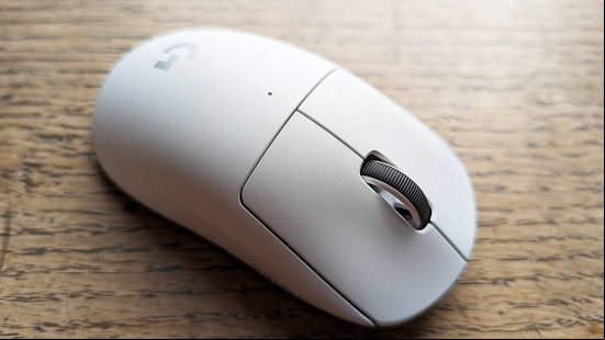 Logitech G Pro X Superlight 2 gaming mouse review: a white Logitech mouse sits on a wooden surface with bright light coming from off-screen.