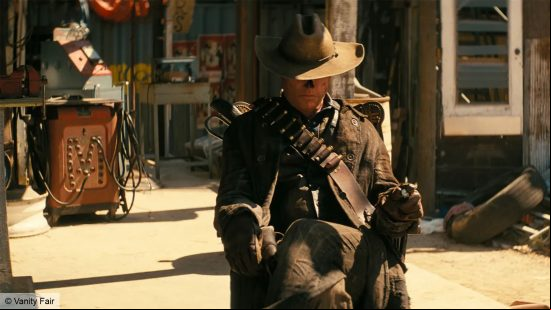A ghoul sitting in a chair, dressed in a brown hat and brown clothes 