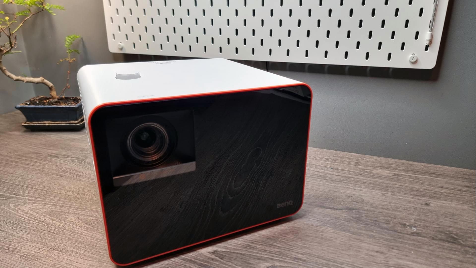 A side angle view of the BenQ X3000i Projector on a gray desktop