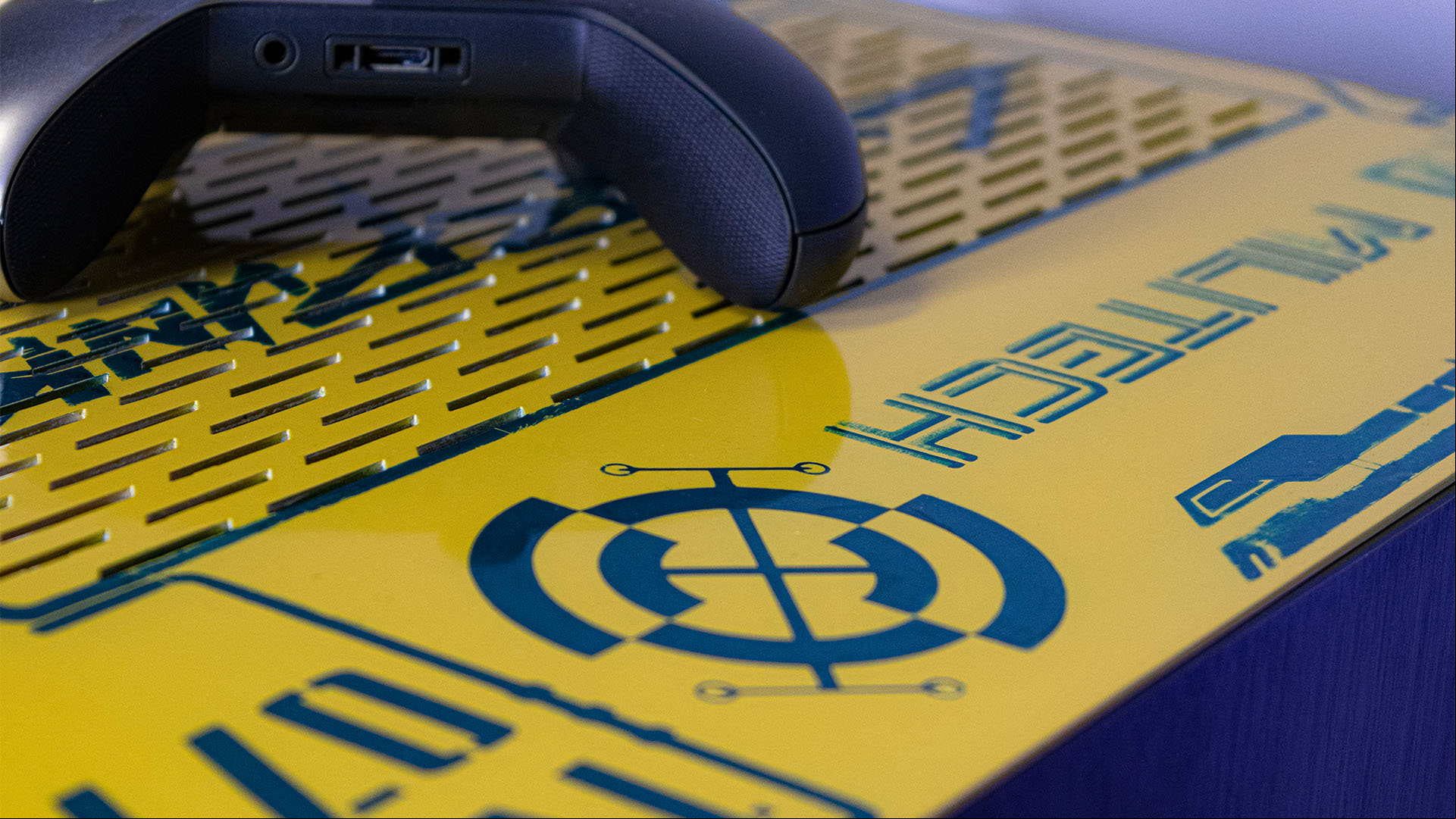 The top  of a custom Cyberpunk 2077 PC build which is bright yellow with cyberpunk iconography