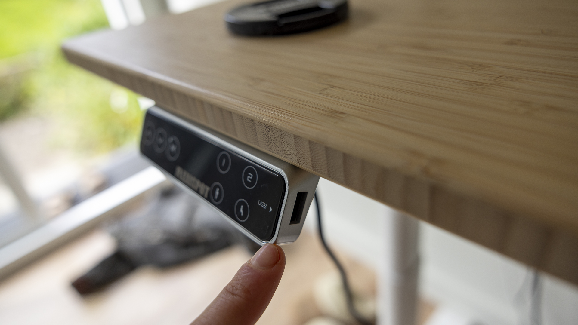 Flexispot E8 Standing Desk review image showing the USB  with a small finger coming towards it.