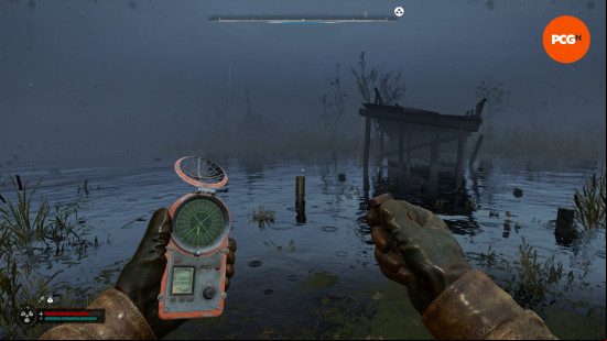 Stalker 2 review: a first person view of someone holding a strange device in one hand, and a large metal bolt in the other.
