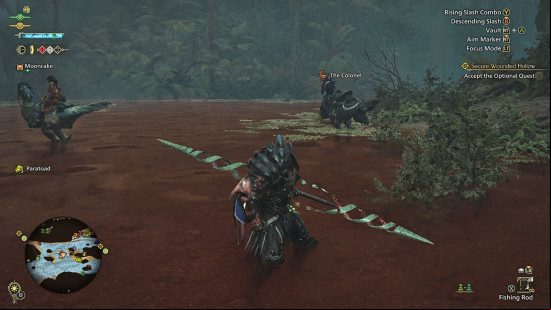 Monster Hunter Wilds Insect Glaive: a man stands calf-deep in a red river, posing with a large spear-like weapon.