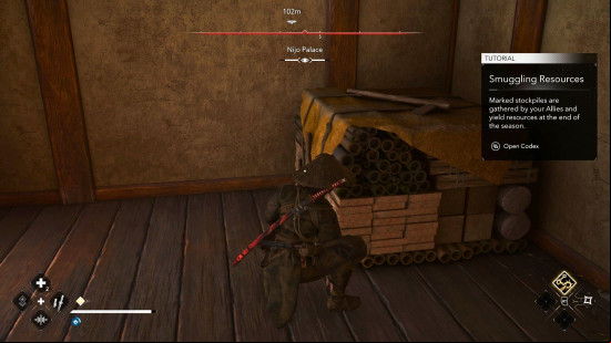 AC Shadows scouts: a female assassin dressed in black attaches a symbol to a large bundle of goods.